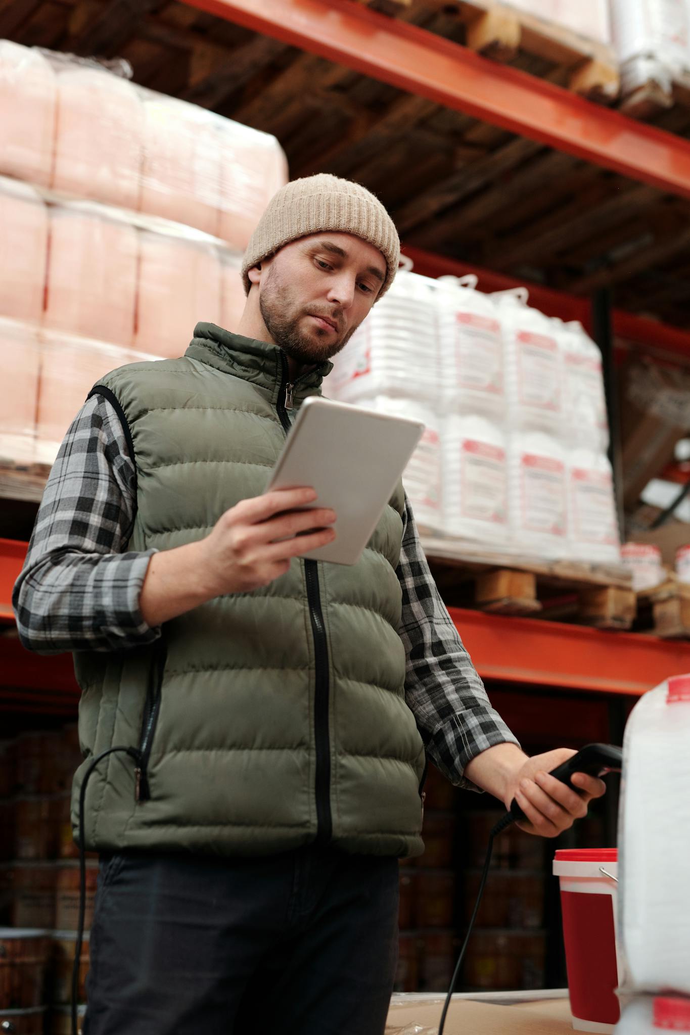 Warehouse employee using a tablet for inventory stock taking in an industrial setting.